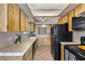 Well-lit kitchen features wooden cabinets, black appliances, and tile countertops at 3339 W Mohawk Ln, Phoenix, AZ 85027