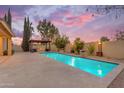 Beautiful backyard pool featuring a stone water feature, adjacent to a covered outdoor patio with a fire pit at 4630 E Hazeltine Way, Chandler, AZ 85249