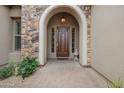 Elegant home entrance featuring a stone archway, a solid wood door, and a well-maintained walkway at 1608 W Calle De Pompas --, Phoenix, AZ 85085