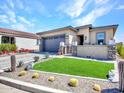 Charming single-story home showcasing lush desert landscaping, artificial turf, and stone accents at 5581 N 206Th Ave, Buckeye, AZ 85396