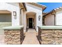 Inviting home exterior features manicured stone entryway, neutral color scheme, and two-car garage at 11818 W Luxton Ln, Avondale, AZ 85323