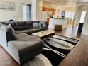 Spacious living room with a large sectional couch, stylish rug, and open access to the kitchen at 12371 W Hadley St, Avondale, AZ 85323