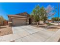 Home showcasing a two-car garage, mature landscaping, and a walkway to the front door at 15573 W Laurel Ln, Surprise, AZ 85379