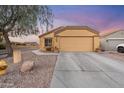 Inviting home exterior featuring a two-car garage and low maintenance desert landscaping at 23932 W Hidalgo Ave, Buckeye, AZ 85326