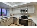 Modern kitchen featuring stainless steel appliances, white cabinets, white countertops, and a view of the backyard at 614 W Kings Ave, Phoenix, AZ 85023