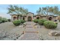 Inviting custom home featuring a brick walkway, lush greenery, and unique architectural design at 7260 E Eagle Crest Dr # 13, Mesa, AZ 85207