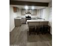 Modern kitchen with gray cabinets, stainless steel appliances, and a breakfast bar with seating for casual dining at 8719 W Monterey Way, Phoenix, AZ 85037