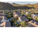 An aerial view showcases a residential area with pools and well-maintained yards against a mountain backdrop at 9443 E Mallory St, Mesa, AZ 85207