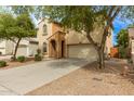 Home featuring a two-car garage, beautiful trees, and desert landscaping at 17507 N Costa Brava Ave, Maricopa, AZ 85139