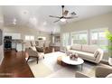 Bright living room featuring hardwood floors, neutral decor, modern furniture, and large windows with natural light at 23063 W Loma Linda Blvd, Buckeye, AZ 85326