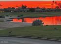 Picturesque view of a golf course pond reflecting a vibrant orange sky at sunset at 2722 N 155Th Dr, Goodyear, AZ 85395