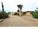 Desert home with an arched gate, gravel yard and palm trees in the front at 6428 E Shea Blvd, Scottsdale, AZ 85254