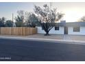 Inviting home with a well-kept lawn, mature trees, and a charming white exterior with dark trim at 7420 N 58Th Ave, Glendale, AZ 85301
