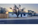 Classic single-story residence featuring a tidy front yard, mature trees, and a freshly painted white facade at 7420 N 58Th Ave, Glendale, AZ 85301