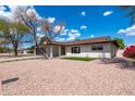 Lovely home with well-maintained landscaping, desert rock, and mature trees against a beautiful blue sky at 8602 E Whitton Ave, Scottsdale, AZ 85251