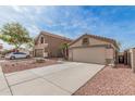 View of beige homes with two-car garages, desert landscaping, and concrete driveways at 11321 W Austin Thomas Dr, Surprise, AZ 85378