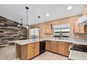 Bright kitchen with light wood cabinets, black appliances, peninsula and a modern accent wall in the dining area at 11321 W Austin Thomas Dr, Surprise, AZ 85378
