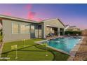 Beautiful backyard featuring a sparkling pool with fountain, a putting green, and a covered patio for outdoor entertaining at 11656 N San Clemente St, Surprise, AZ 85388