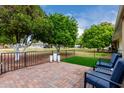 Outdoor patio area with brick flooring, black metal fencing, and comfortable seating overlooking a green lawn at 17822 N Del Webb Blvd, Sun City, AZ 85373