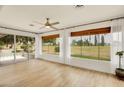 Inviting sunroom with wood-look tile, ceiling fan, and large windows offering picturesque views at 18607 N 125Th Ave, Sun City West, AZ 85375