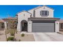 Stylish home featuring a grey two car garage door, an arched entry and desert landscaping at 2377 S 245Th Dr, Buckeye, AZ 85326