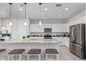 Modern white kitchen with stainless steel appliances, granite countertops, and bar stool seating at 2377 S 245Th Dr, Buckeye, AZ 85326