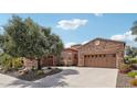 Charming home exterior with stone accents, mature landscaping, and circular driveway at 27926 N 130Th Ave, Peoria, AZ 85383