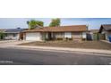 Charming home features a desert front yard with mature landscaping and brick accents; white garage door and front door entryway at 402 W Mohawk Ln, Phoenix, AZ 85027
