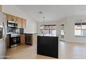 Open kitchen area with stainless steel appliances, wooden cabinetry, black countertops, and a large kitchen island at 438 E Hackamore St, Mesa, AZ 85203