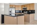 Stylish kitchen featuring wooden cabinets, a black countertop island, and modern stainless steel appliances at 438 E Hackamore St, Mesa, AZ 85203