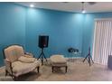 Bright living room features cozy armchair, ottoman, turquoise walls and tile floor at 4549 W Seldon Ln, Glendale, AZ 85302