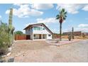 A bright two-story white house with desert landscaping and a gravel driveway sits under a partly cloudy sky at 5599 S Alameda Rd, Gold Canyon, AZ 85118