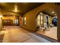 Inviting covered patio with hanging lights, rocking chairs, and access to the garage and back door at 21266 S 213Th Pl, Queen Creek, AZ 85142