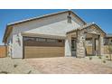 Home featuring a large brown garage door, brick driveway, and stylish architectural details for enhanced curb appeal at 25188 N 174Th Ave, Surprise, AZ 85387