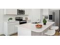 Modern kitchen featuring stainless steel appliances, an island with quartz countertops, and white cabinetry at 25251 N 183Rd Dr, Wittmann, AZ 85361