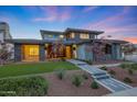 Inviting two-story home featuring a modern design, manicured lawn, stone accents, and a welcoming entrance with custom walkway at 4098 N Golf Dr, Buckeye, AZ 85396