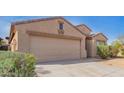 Tan single-story home with a two-car garage, desert landscaping and some greenery under a blue sky at 1541 W Lynne Ln, Phoenix, AZ 85041