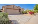 Tan single-story home with a two-car garage, desert landscaping and some greenery under a blue sky at 1541 W Lynne Ln, Phoenix, AZ 85041