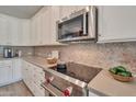 Close-up of the kitchen featuring a stainless steel oven, microwave, and custom backsplash at 16911 W Palm Ln, Goodyear, AZ 85395