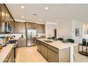 Modern kitchen featuring stainless steel appliances, spacious island with sink, and ample cabinetry at 17341 W Fallen Leaf Ln, Surprise, AZ 85387