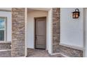 Inviting front entrance featuring a sturdy, earth-toned door framed by elegant stone accents and a stylish outdoor lantern at 17827 W Medlock Dr, Litchfield Park, AZ 85340