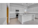 Modern, all-white kitchen featuring a large island with a sink, stainless steel appliances, and ample counter space for cooking at 17827 W Medlock Dr, Litchfield Park, AZ 85340