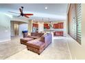 Open-concept living room showcasing tile floors, ceiling fan, and seamless flow into the kitchen at 18107 W Thunderhill Pl, Goodyear, AZ 85338