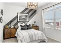 Stylish bedroom with a modern light fixture, gray striped accent wall, and natural light at 18353 W Gray Fox Trl, Wittmann, AZ 85361