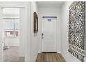 Inviting hallway featuring a white door, wooden floors, and a view into a bedroom at 18353 W Gray Fox Trl, Wittmann, AZ 85361