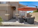 Relaxing outdoor patio area features a table with four chairs, a fire pit and a large parasol umbrella at 19616 N Toya St, Maricopa, AZ 85138