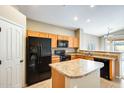 Functional kitchen with wooden cabinets, tile flooring, black appliances, and an island at 1979 N Vista Ln, Casa Grande, AZ 85122