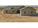 A front view of a newly constructed home featuring neutral tones and a desert landscape at 25721 W Running Deer Trl, Wittmann, AZ 85361