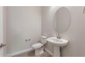 Bright half bathroom featuring a round mirror and pedestal sink at 26696 W Siesta Ln, Buckeye, AZ 85396