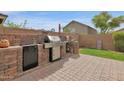 Outdoor kitchen featuring stainless steel grill, mini refrigerator, and brick accents at 4364 S Tatum Ln, Gilbert, AZ 85297